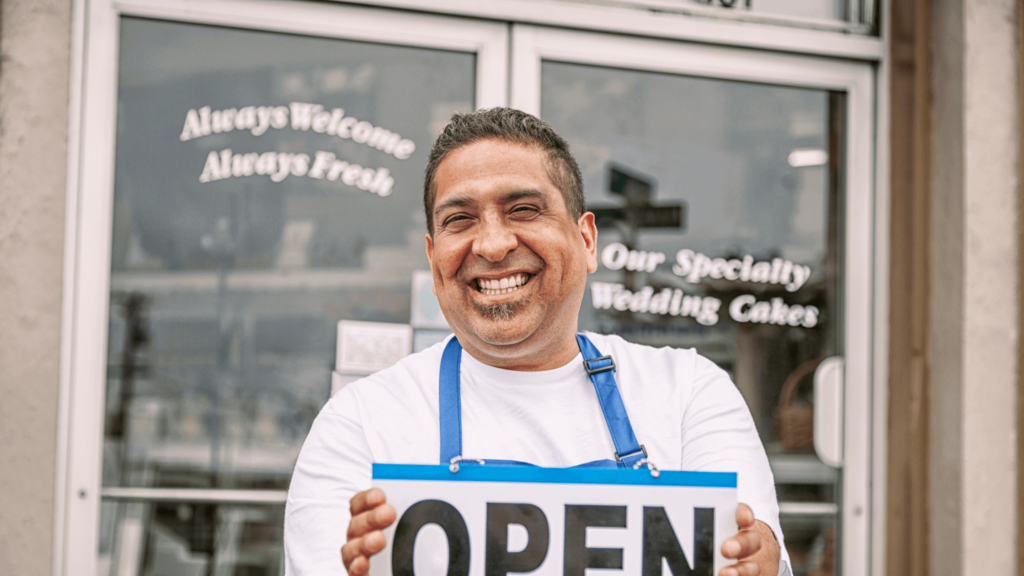 man holding open sign in front of business to signify he calimed his google business profile